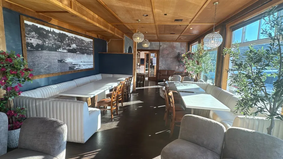 The large-party area: long white banquettes down both sides of the room, with tables between them