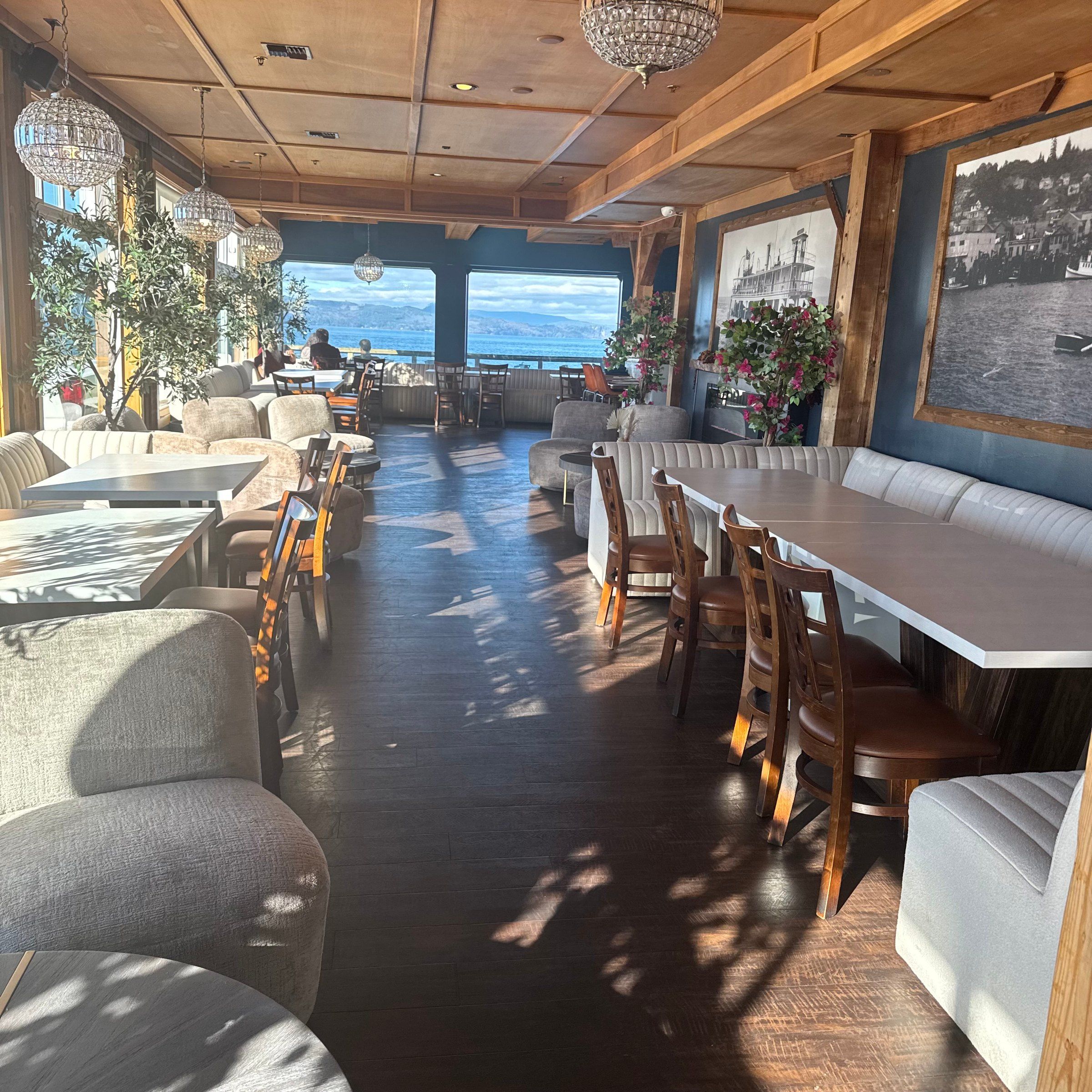 The lounge at Akres: sofas and armchairs by the fireplace, with tables and the river windows beyond