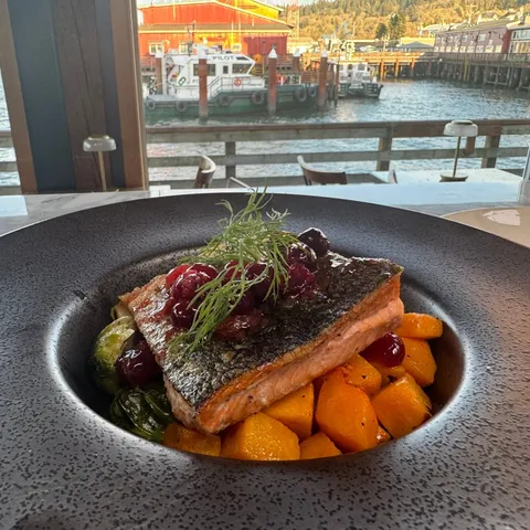 Seasonal Salmon on a dark plate with the river and the waterfront behind it